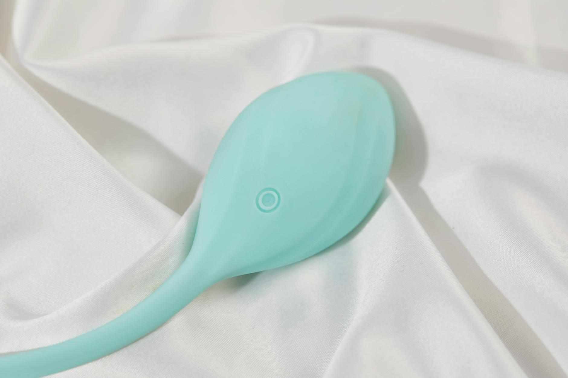 A teal lemon vibrator on white silk, symbolizing modern pleasure tools for couples