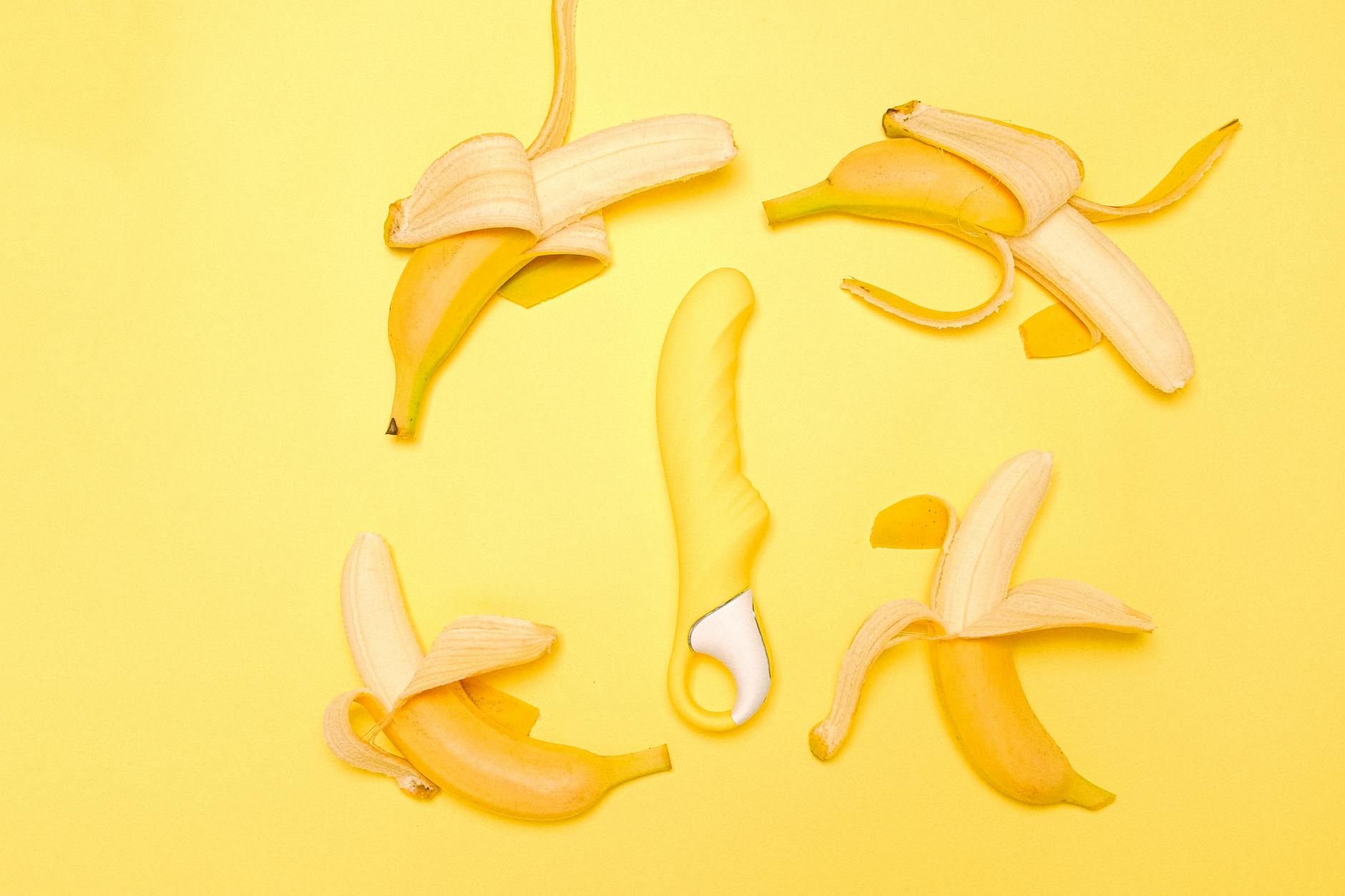Yellow lemon clitoral vibrator surrounded by fresh lemons on bright yellow background