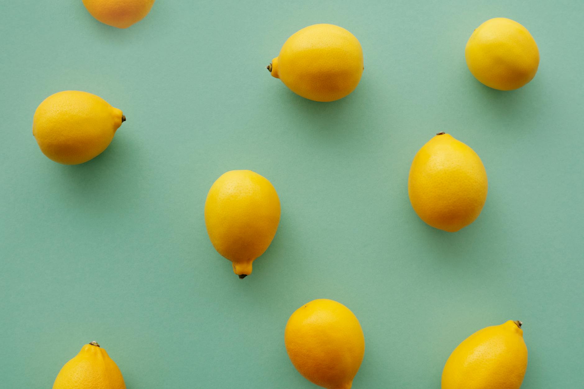 Bright yellow lemons arranged on a pastel green background, representing fresh sensation and vibrant pleasure