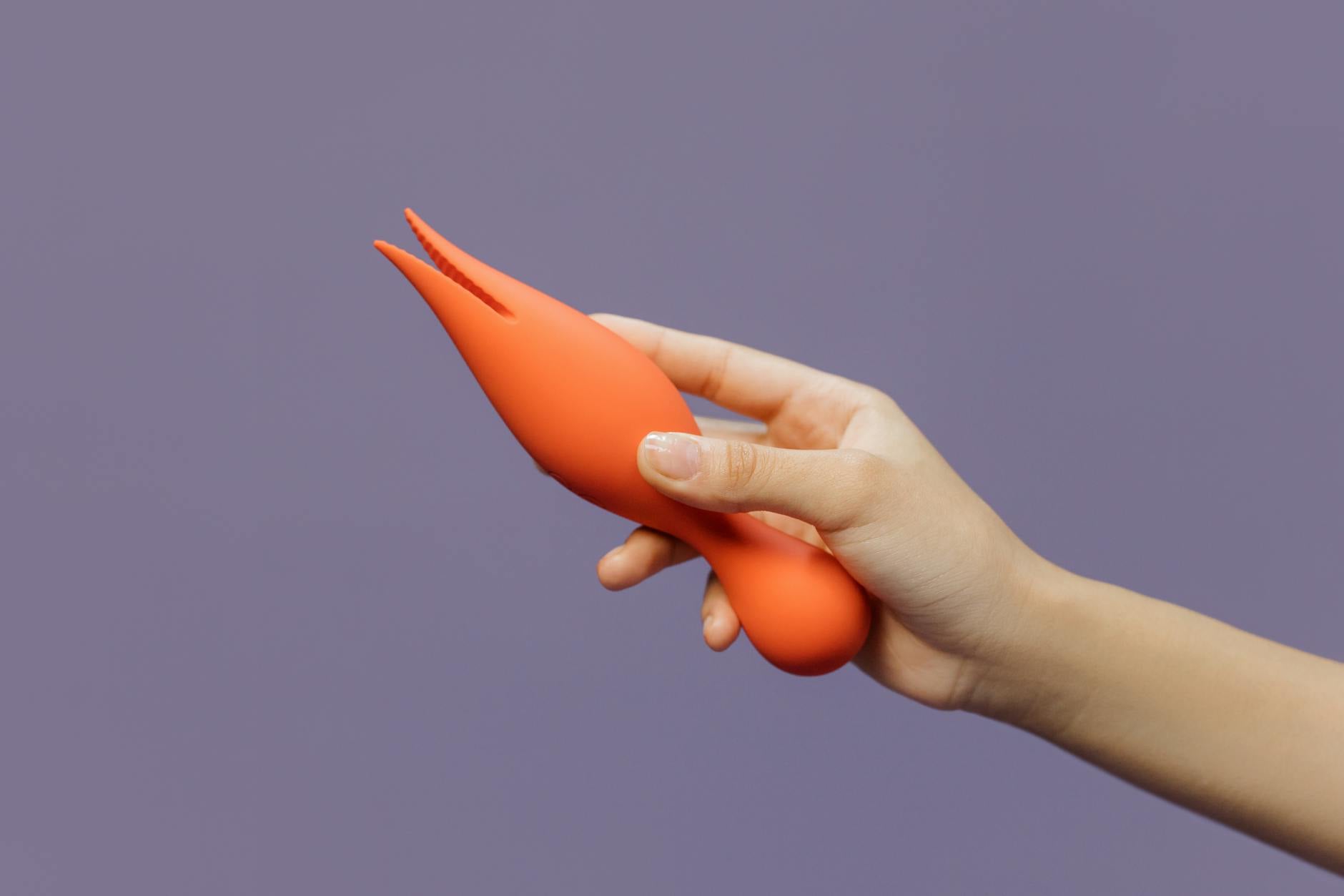 A hand holding a lemon-colored vibrator against a minimalistic purple backdrop, showcasing modern sensuality.
