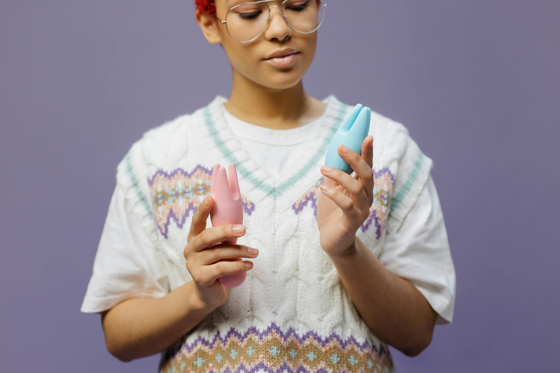 Woman thoughtfully holding a blue clitoral vibrator, exploring pleasure and sensation